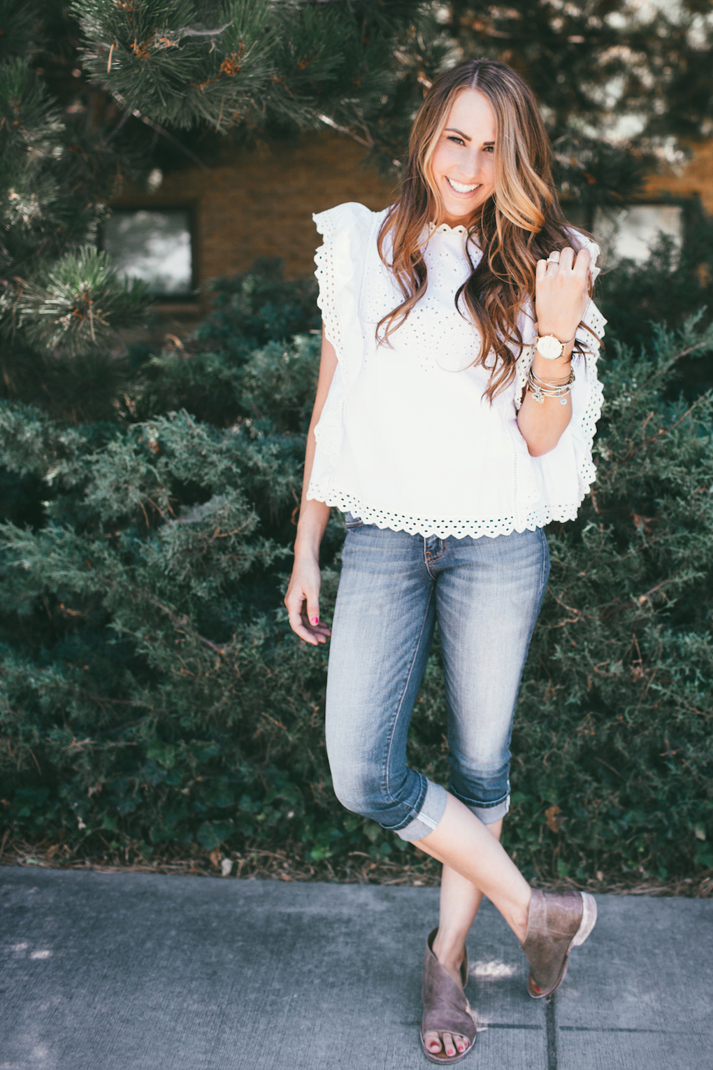 Girl in white eyelet top with crops on with watch and bracelets