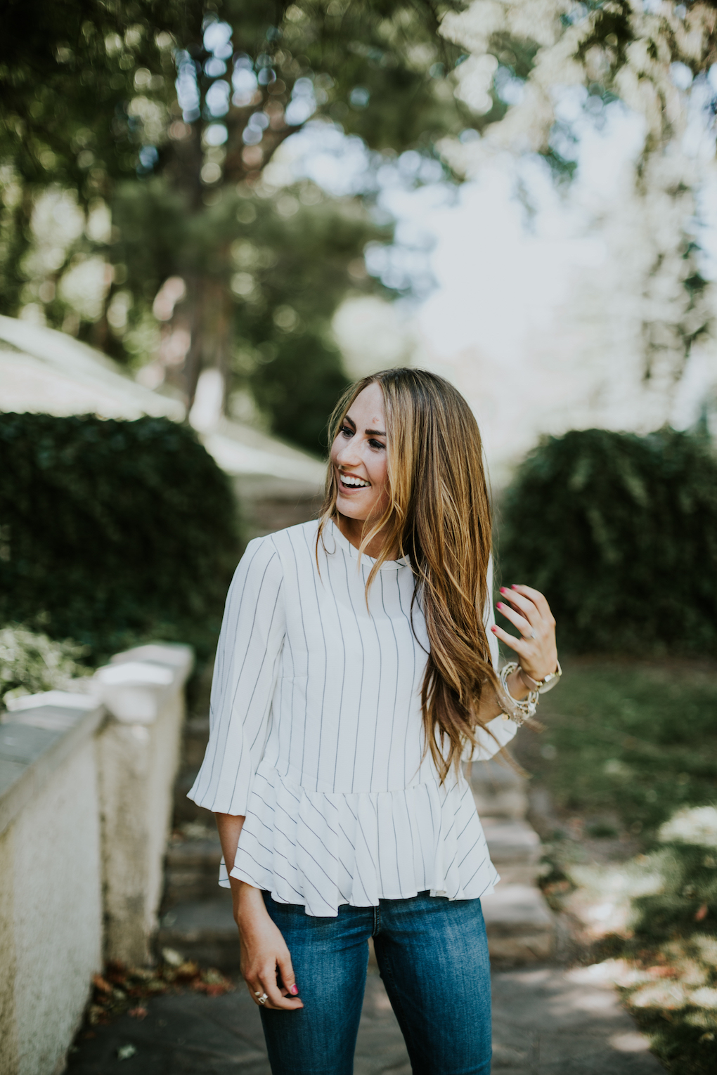 girl laughing wearing black and white stripe peplum top that is oversized and high waisted denim jeans