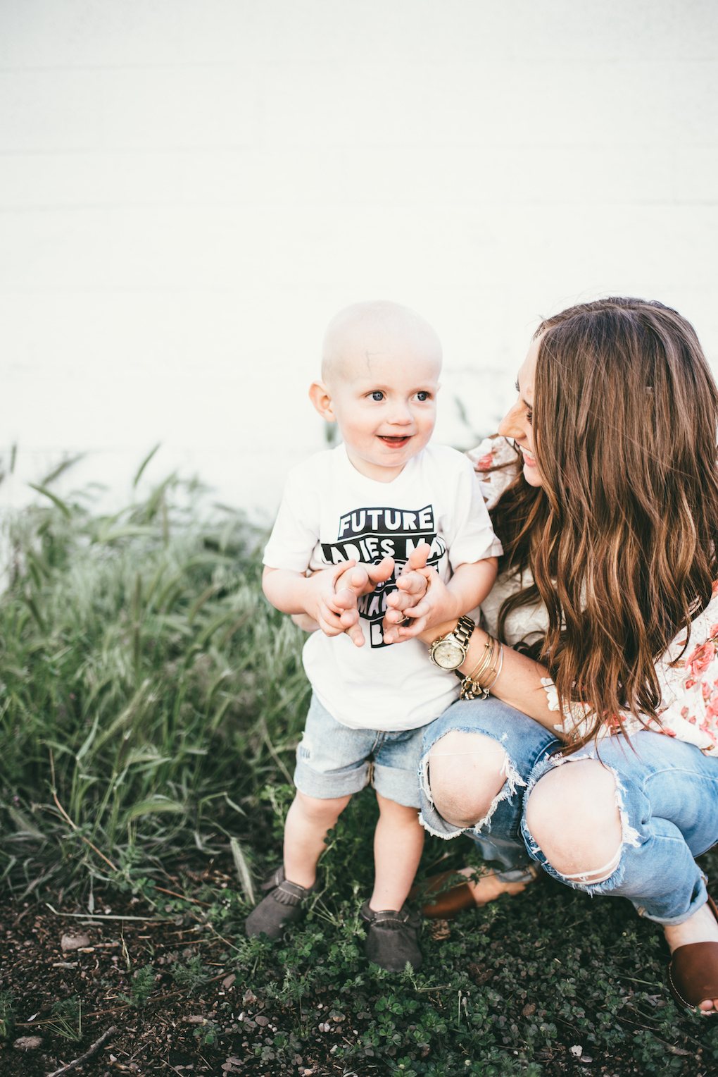 little boy in white graphic tee in cut off denim shorts with his mom