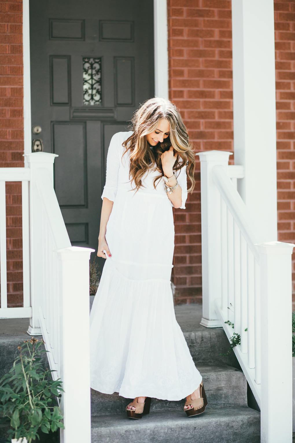 Girl in long white embroidered maxi dress with long loose caramel and brown curls