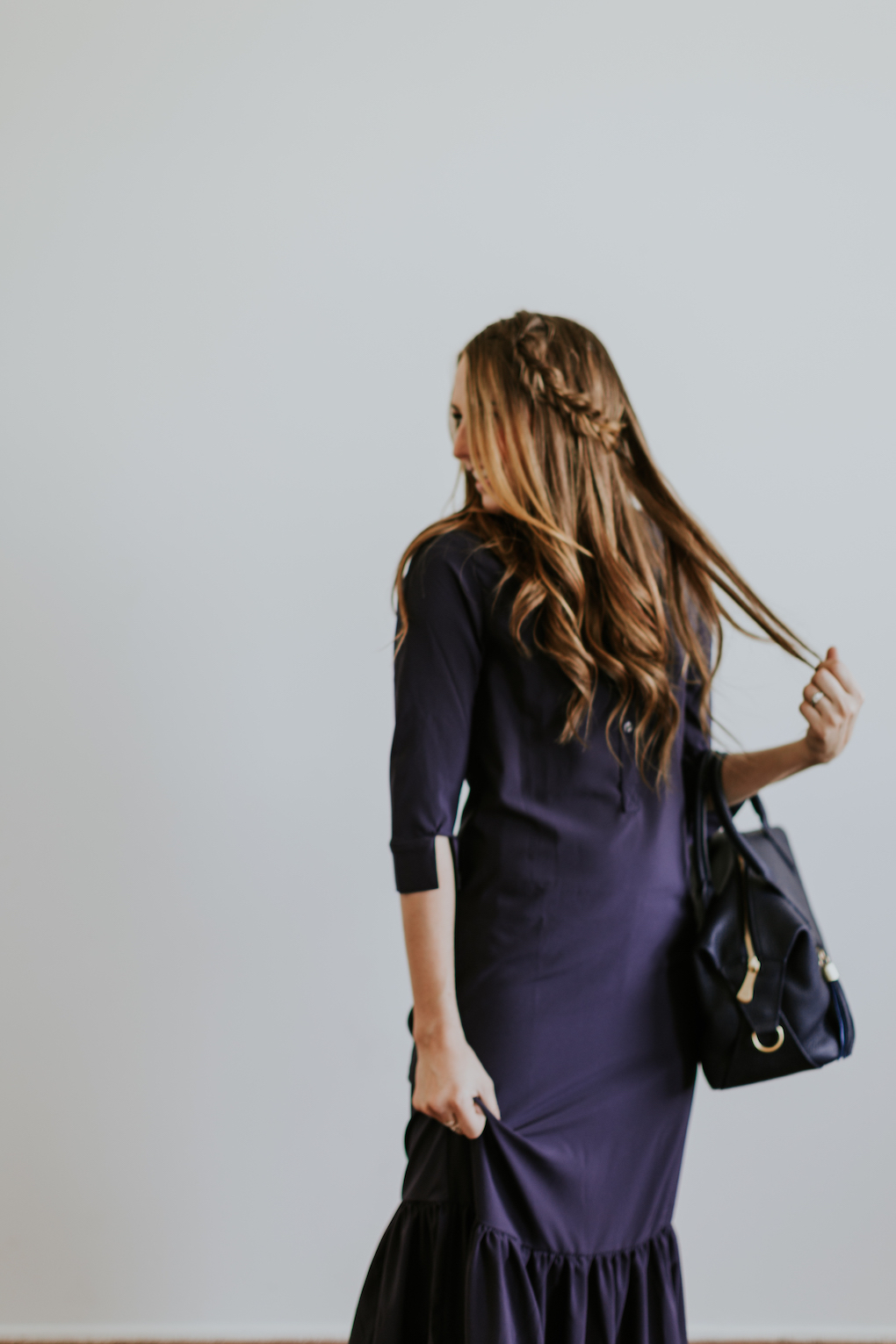 Girl with fishtail braid wearing long navy maxi dress with ruffle and a navy gigi new york bag