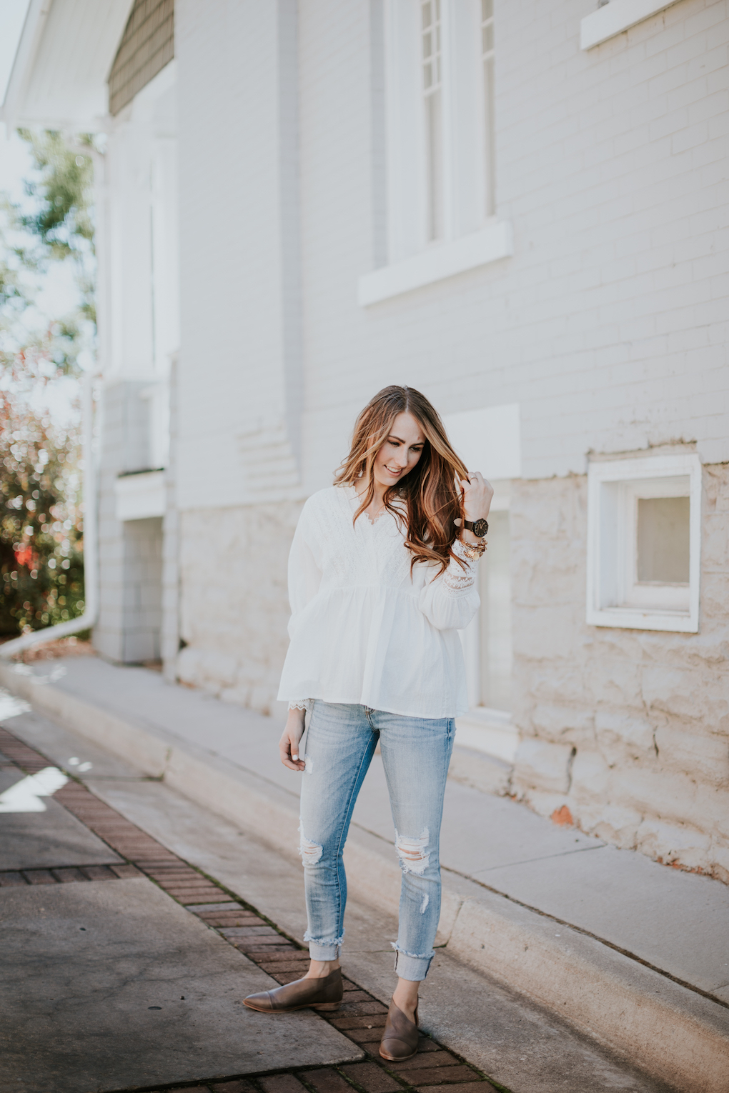 girl with brown hair and caramel highlights wearing white long sleeve lace detail top