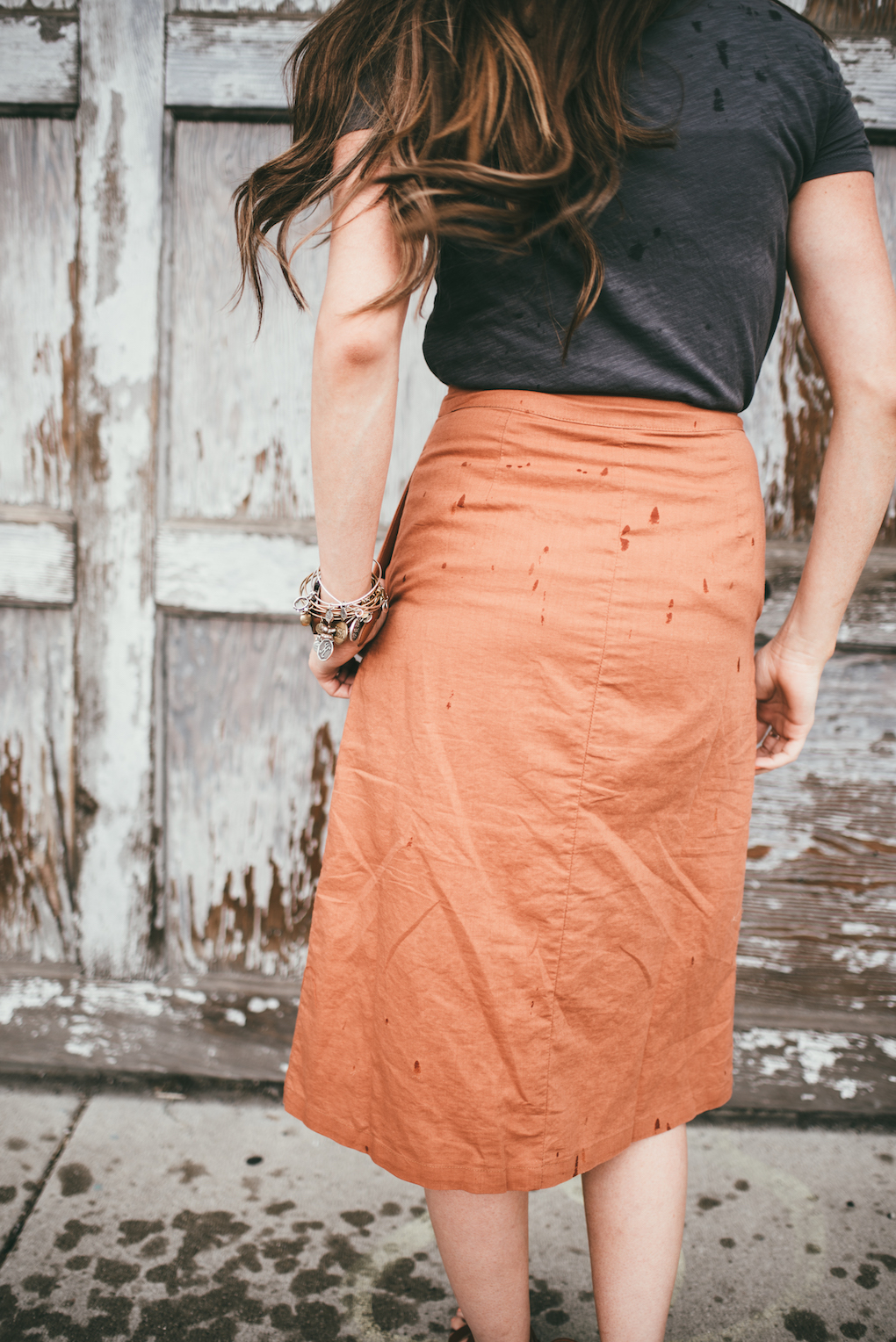 orange button up midi skirt with grey tee shirt girl standing in front of old distressed white garage door