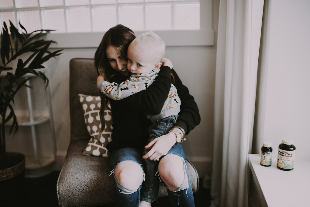 Girl sitting in chair playing with little boy and cuddling him in front room girl wearing ILY Couture Sweatshirt and distressed denim little boy in Superhero Sweatshirt