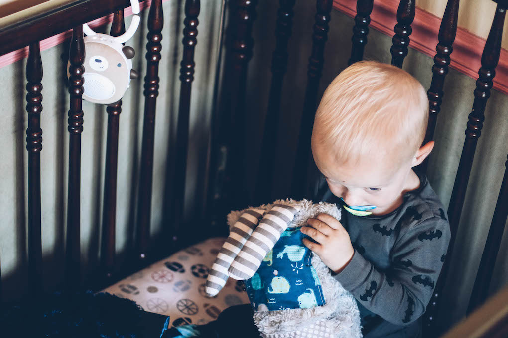 little boy sitting in crib playing with Soundbub