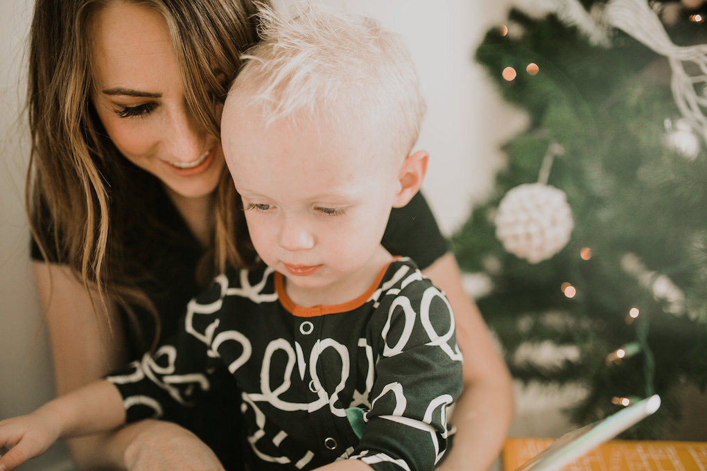 mom and little boy snuggling by christmas tree and little boy in rags to raches romper