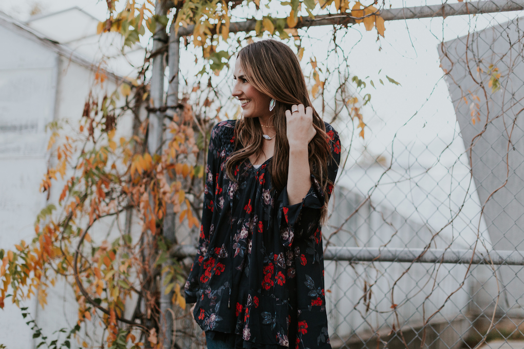 free people long floral navy top with dainty layered necklaces distressed jeans booties long loose curled brown hair with caramel highlights