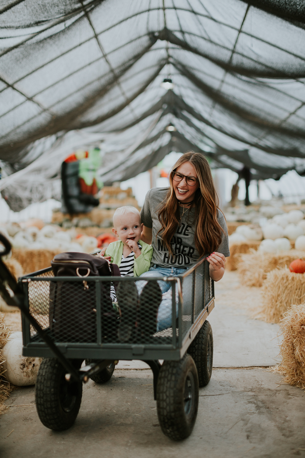 mom and little boy sitting in wagon at the pumpkin patch
