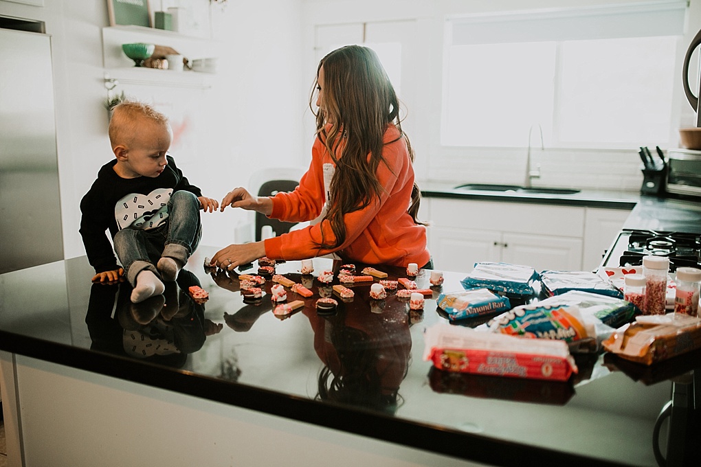 mom and little boy sitting in kitchen wearing valentines sweatshirts making 3 5 minute valentine treat recipes to make with your toddler chocolate dipped wafer cookies oreos and marshmallows