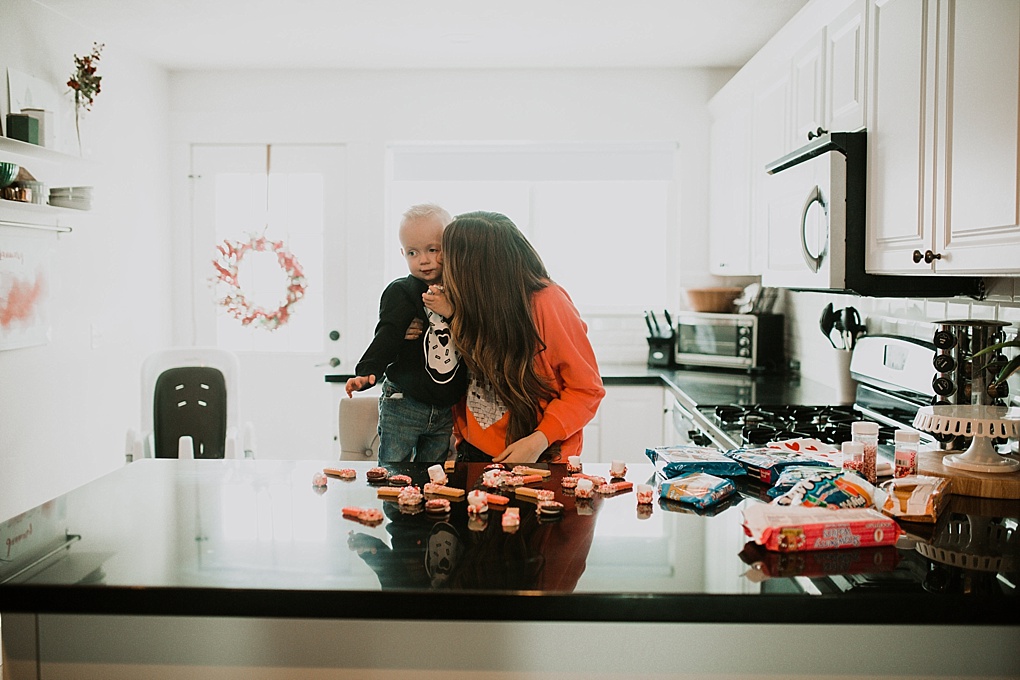 mom and little boy sitting in kitchen wearing valentines sweatshirts making 3 5 minute valentine treat recipes to make with your toddler chocolate dipped wafer cookies oreos and marshmallows