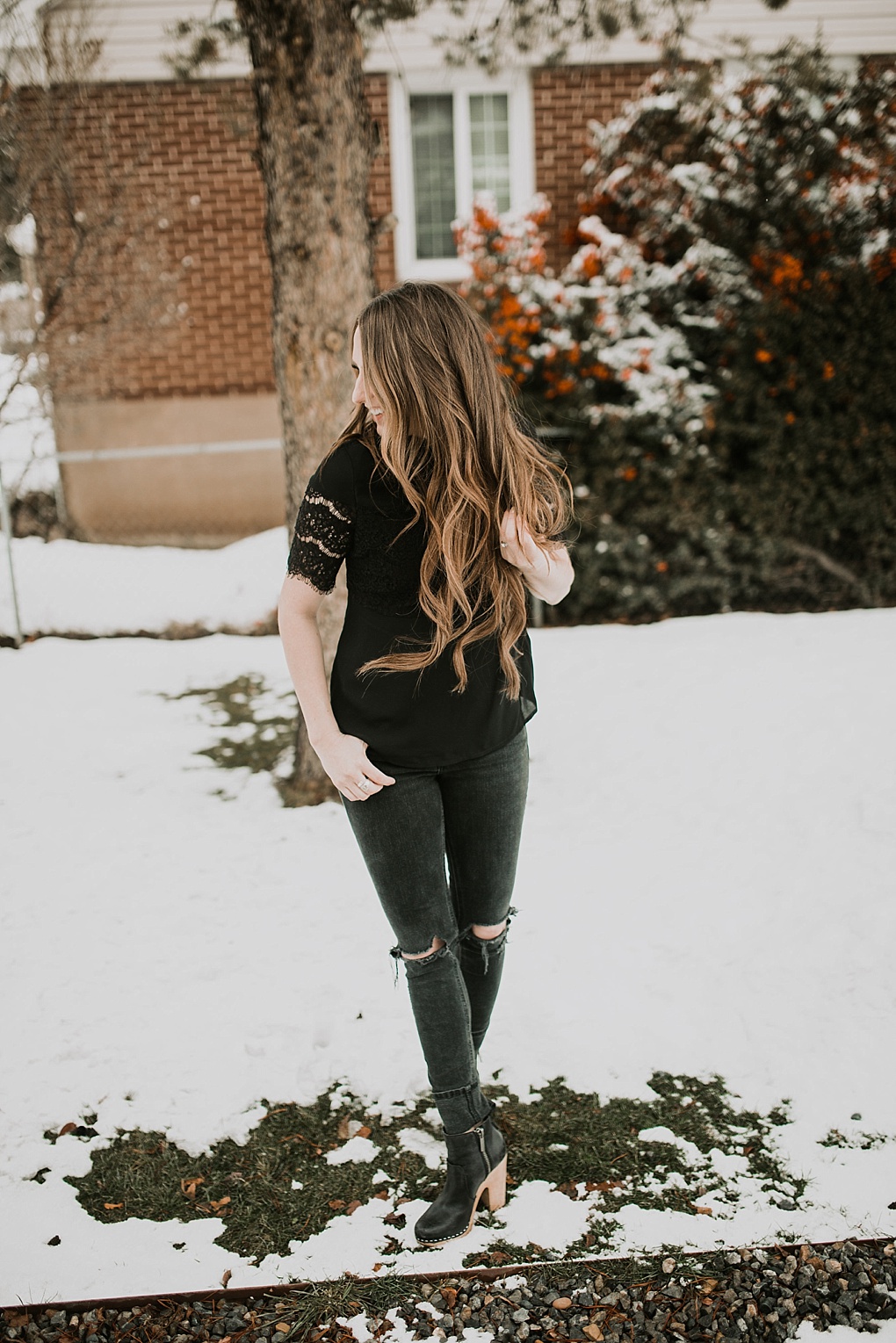 girl standing in snow in black lace top with black jeans and nike boots
