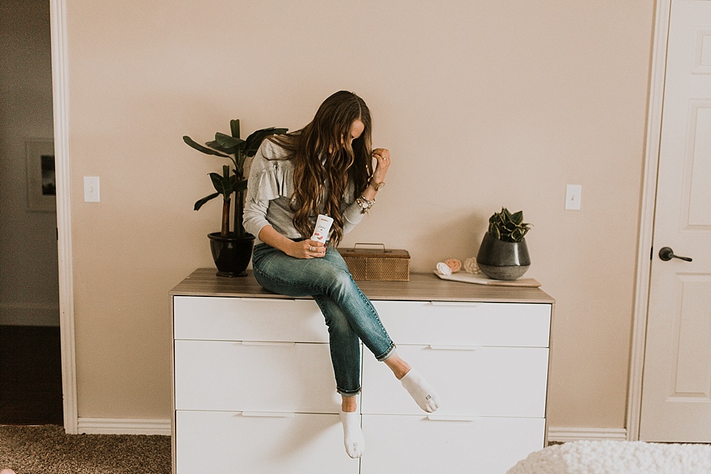 girl sitting on dresser in ruffled sweatshirt with dove deodorant with long loosely curled brown hair