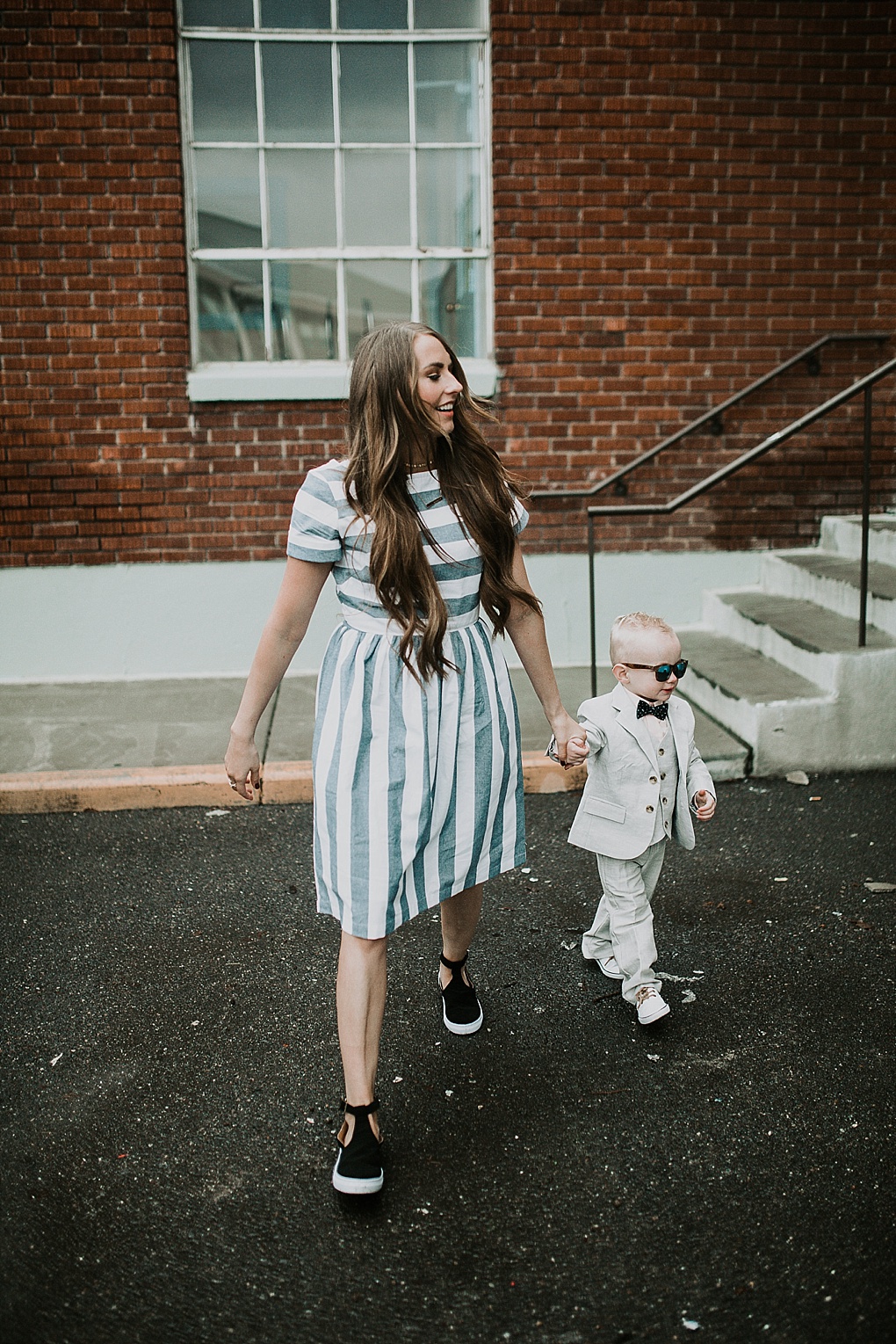 mom and little boy walking little boy in janie and jack linen suit and mom in blue and white stripe shabby apple dress