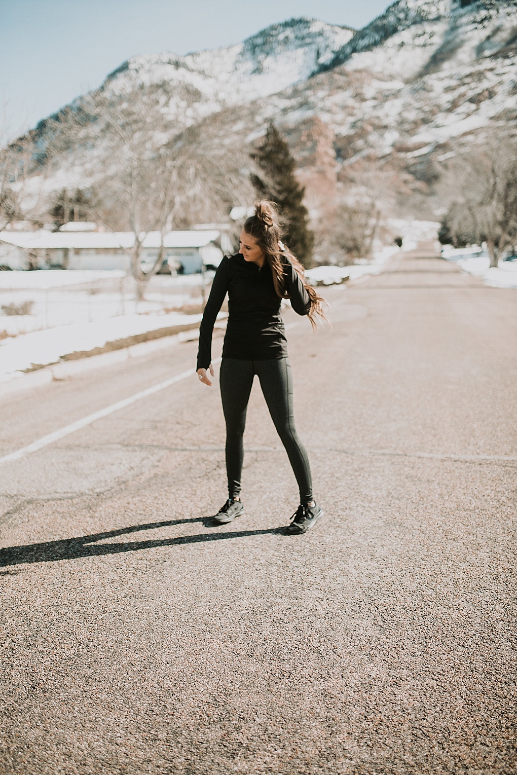 girl standing in road in senita athletics half zip jacket and yoga pants with half up top knot