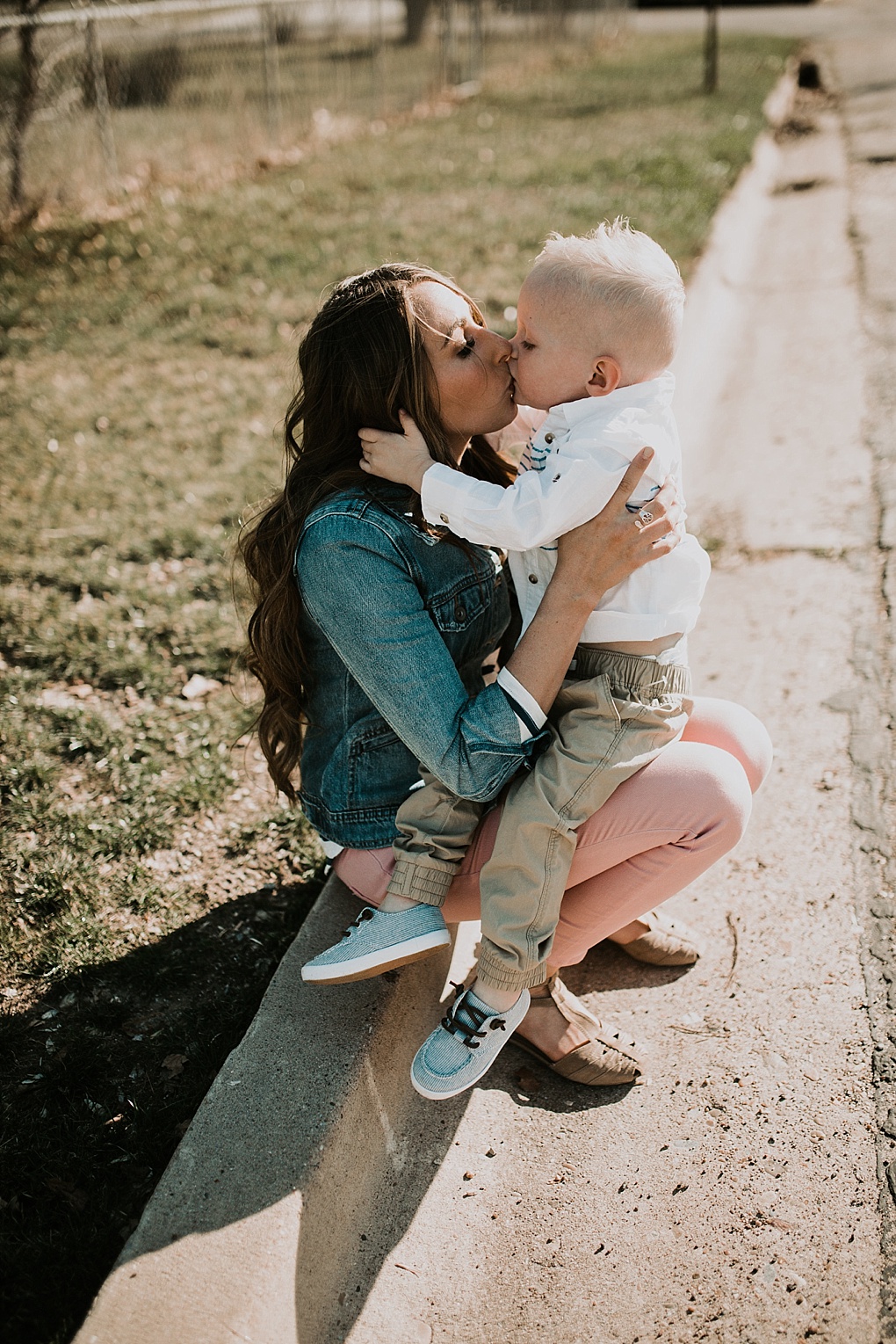 mom in blush pants with nautical stripe old navy top and jean jacket walking in the road with little boy in khaki joggers and white button up with blue stripes