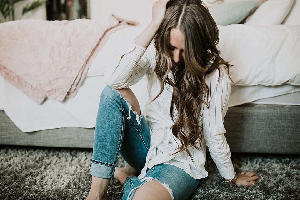 girl sitting on bed in white topshop tie top with distressed jeans and long loose curls and caramel highlights with brittany spears fragrence