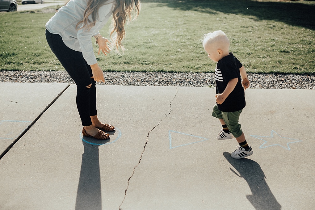 little boy playing outside games with his family football catch blowing bubbles jumping on shapes in june and january wiht mom in denim button down and black jeans with long loosely curled brown hair with caramel highlights