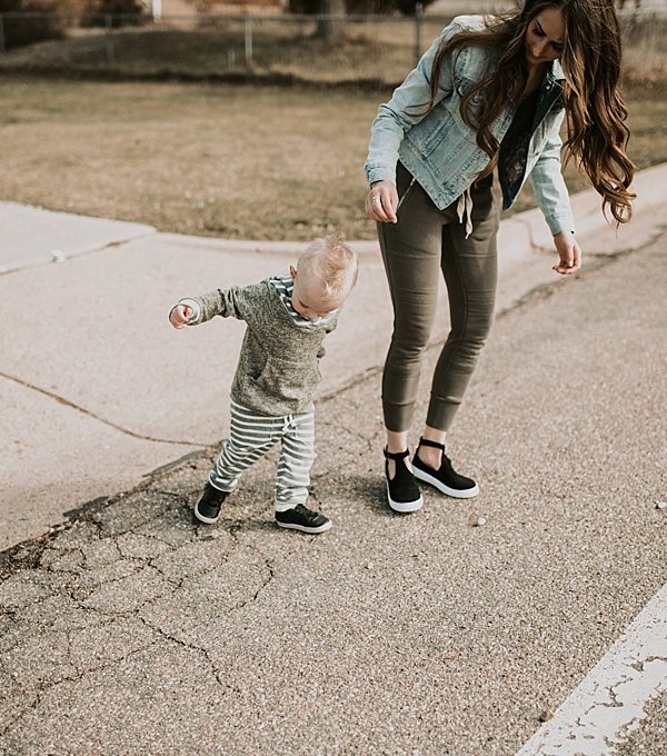 mom in jogger sweats with denim jacket and little boy in lulu and roo sweat outfit walking in the street little boy in freshly picked moccs