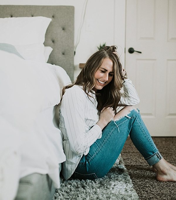 girl sitting on bed in white topshop tie top with distressed jeans and long loose curls and caramel highlights with brittany spears fragrence